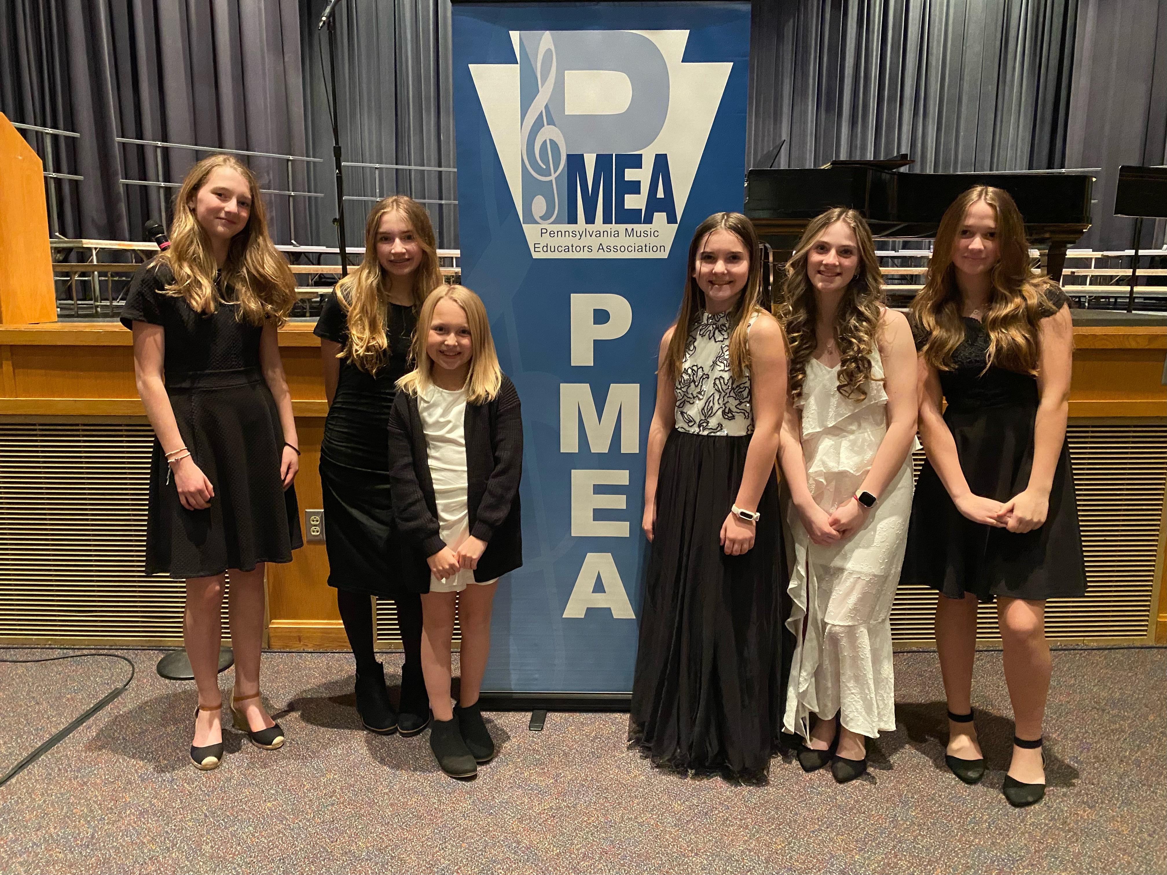 posed group of students standing by a PMEA sign